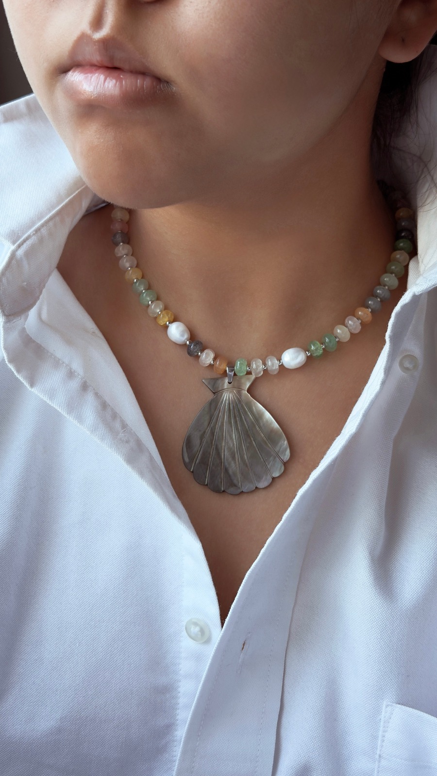 Handcrafted shell pendant necklace worn with a white shirt
